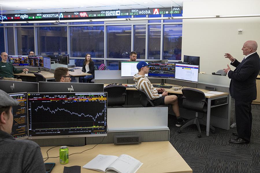 Students sit in desks around the room in a finance class.