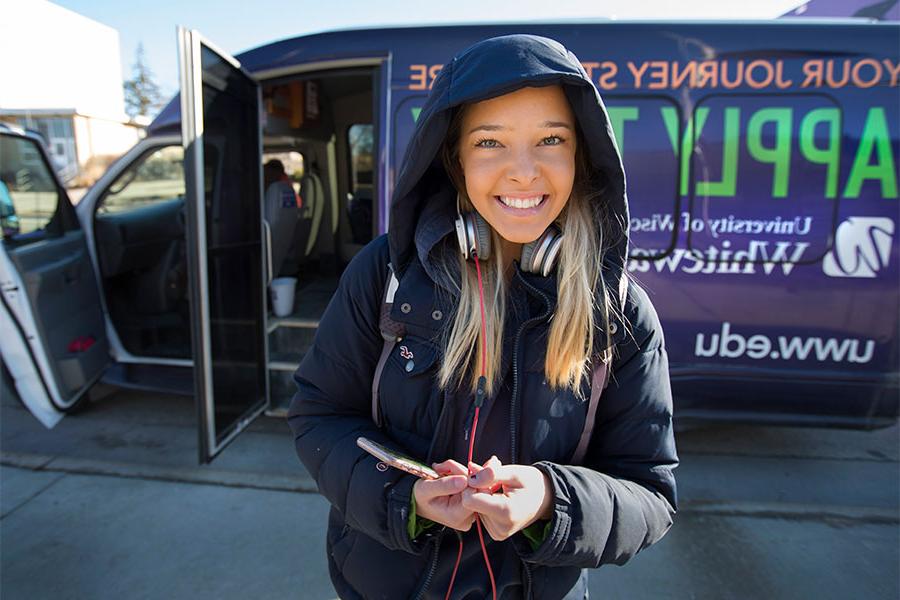 Student in front of shuttle bus.